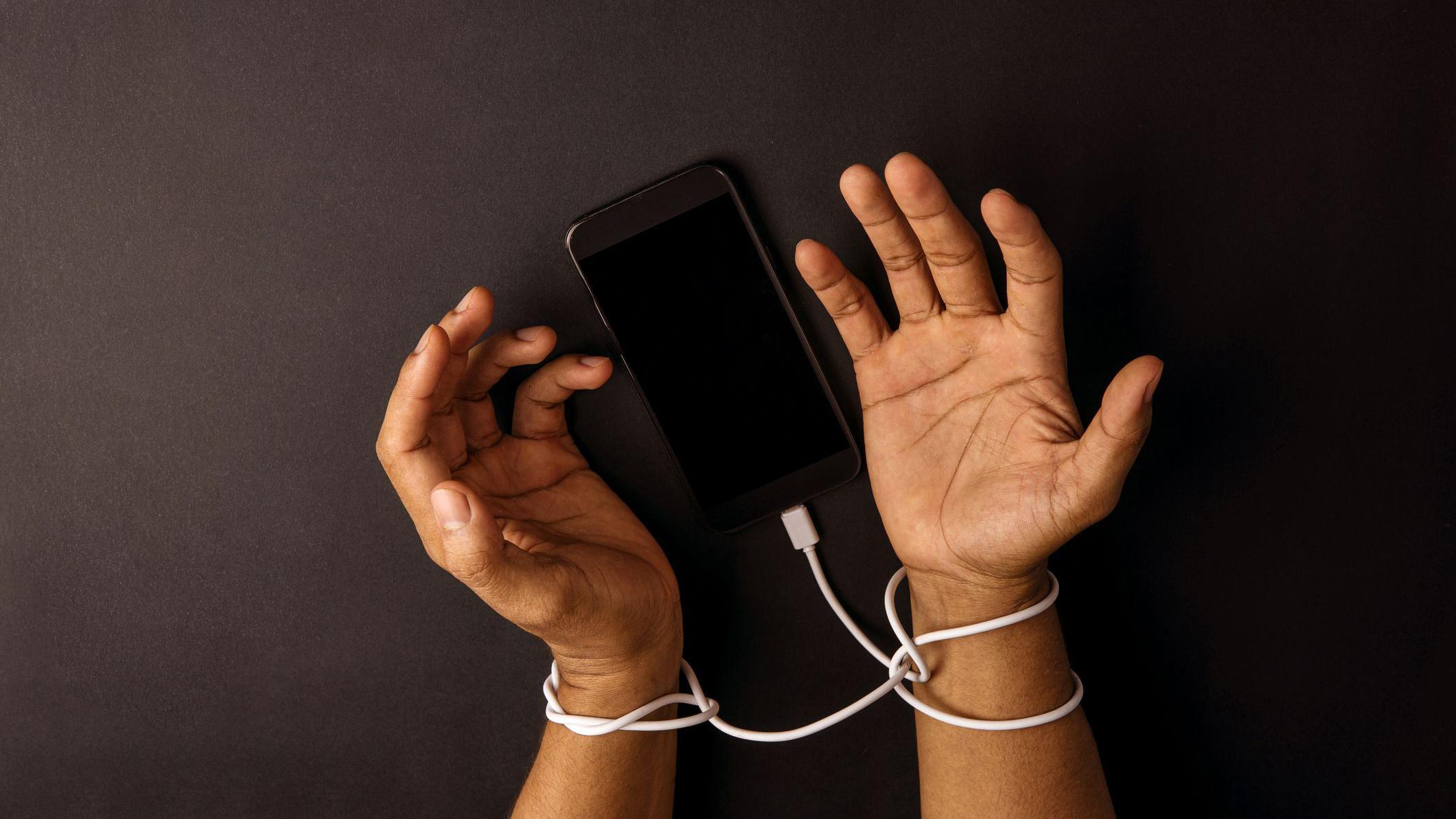 يدان مقيدتان بسلك شاحن الهاتف المحمول. - Getty Images