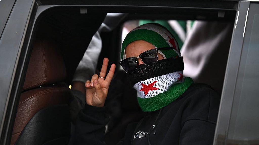 سيدة تشير بعلامة النصر خلال احتفالات في دمشق بمناسبة الذكرى الأولى لسقوط الأسد (8 ديسمبر/ كانون الأول 2025) - Louai Beshara / AFP / Getty Images