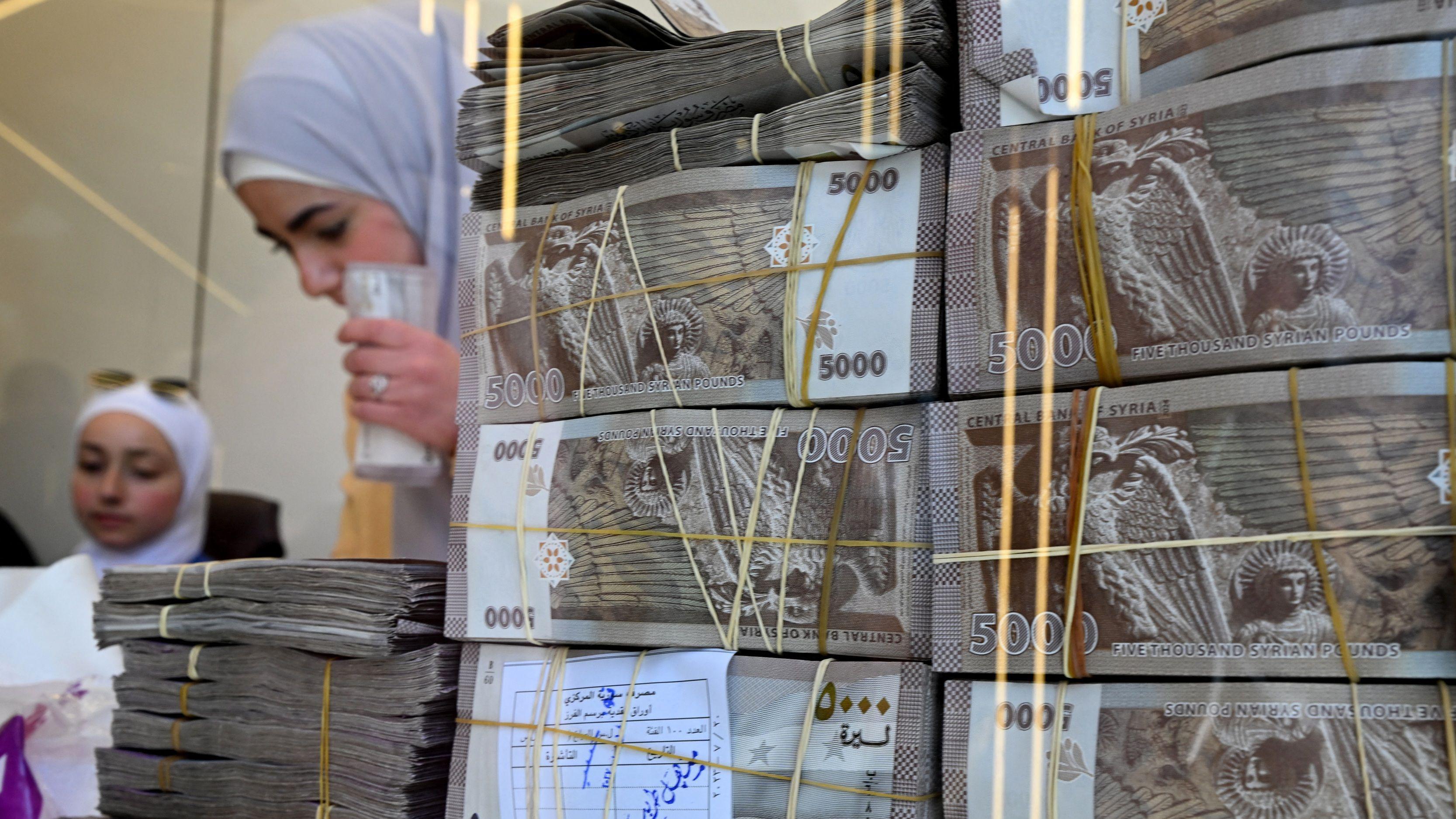 أكوام من الأوراق النقدية السورية في محل صرافة في دمشق، في 16 أبريل/نيسان 2025 - AFP via Getty Images