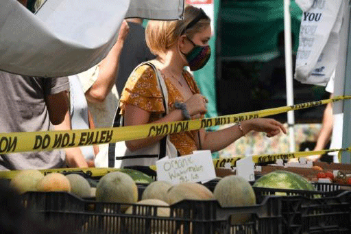 امرأة ترتدي كمامة تشتري بطيخاً من سوق في سانتا مونيكا، كاليفورنيا، في الأول من أغسطس 2020