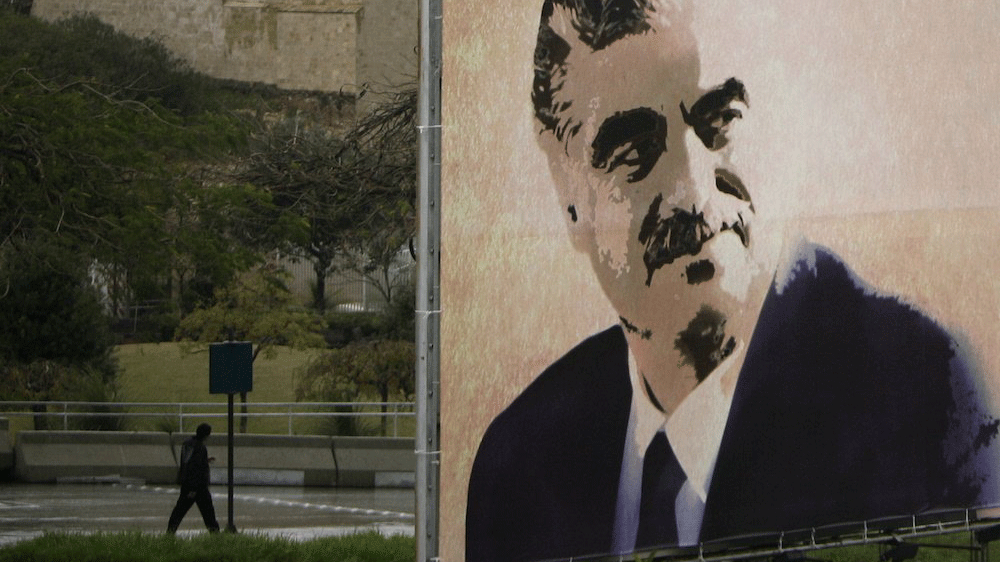 رجل يمر في وسط بيروت بالقرب من صورة عملاقة للرئيس الأسبق رفيق الحريري في ذكري اغتياله، 14 فبراير 2011