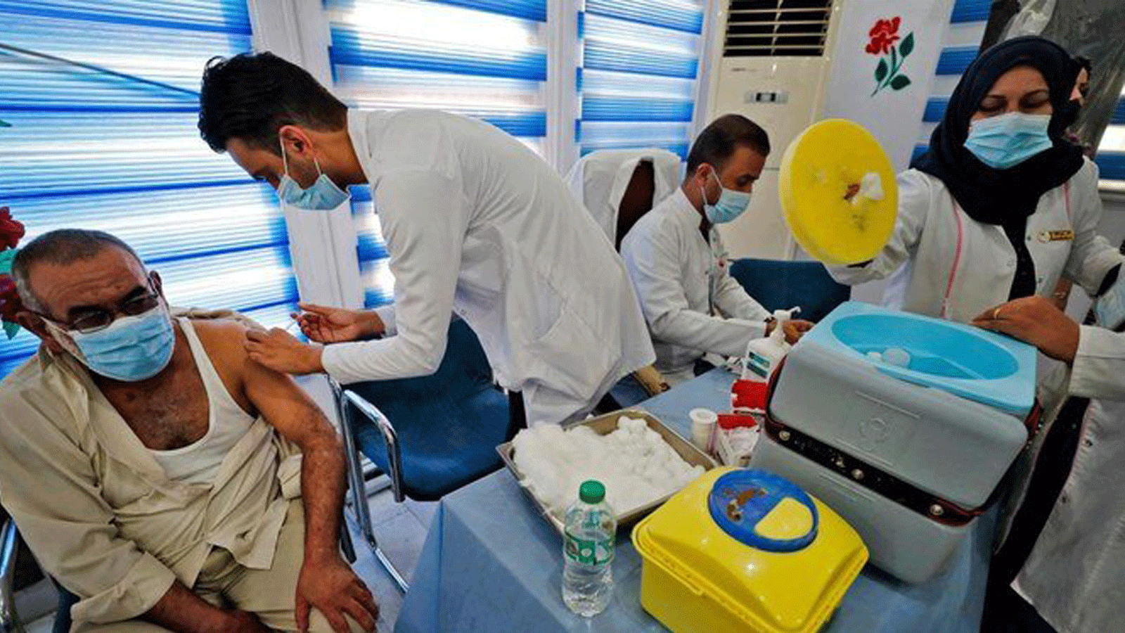 مسعفون عراقيون يقدمون لقاح Pfizer-BioNTech COVID-19 للأشخاص في مركز التطعيم في بغداد. 