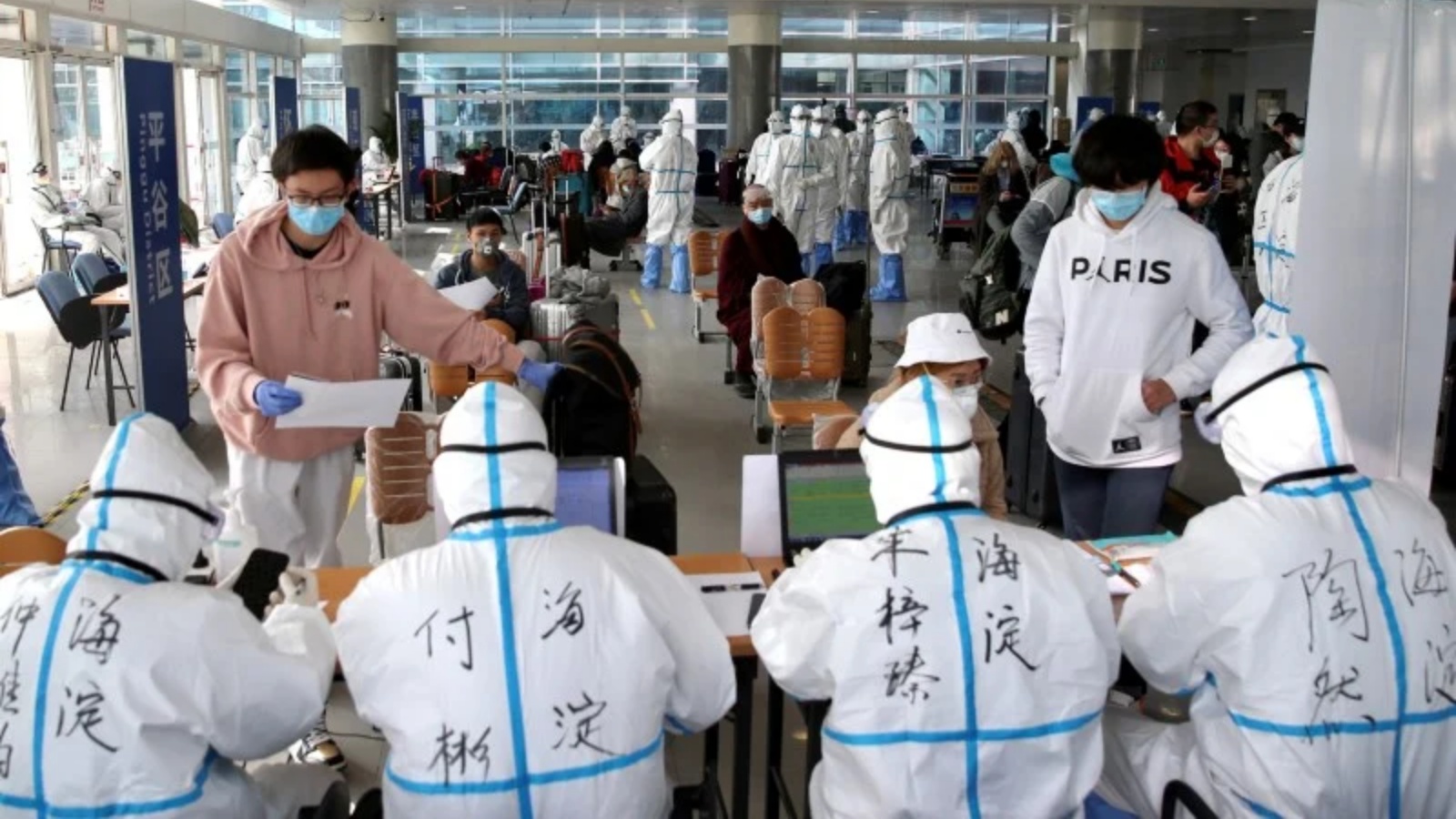 عمال صحيون يرتدون بدلات عازلة في المطار عملاً بقيود مكافحة كوفيد-19 في بكين 