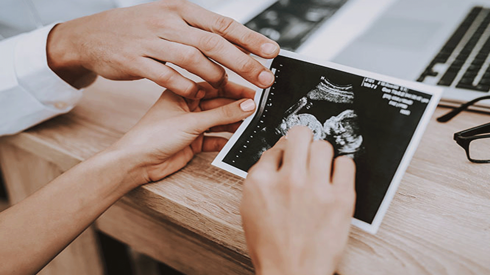 صورة توضحية: طبيب يناقش صحة الجنين من خلال صورة UltraSound تكشف وضعيته