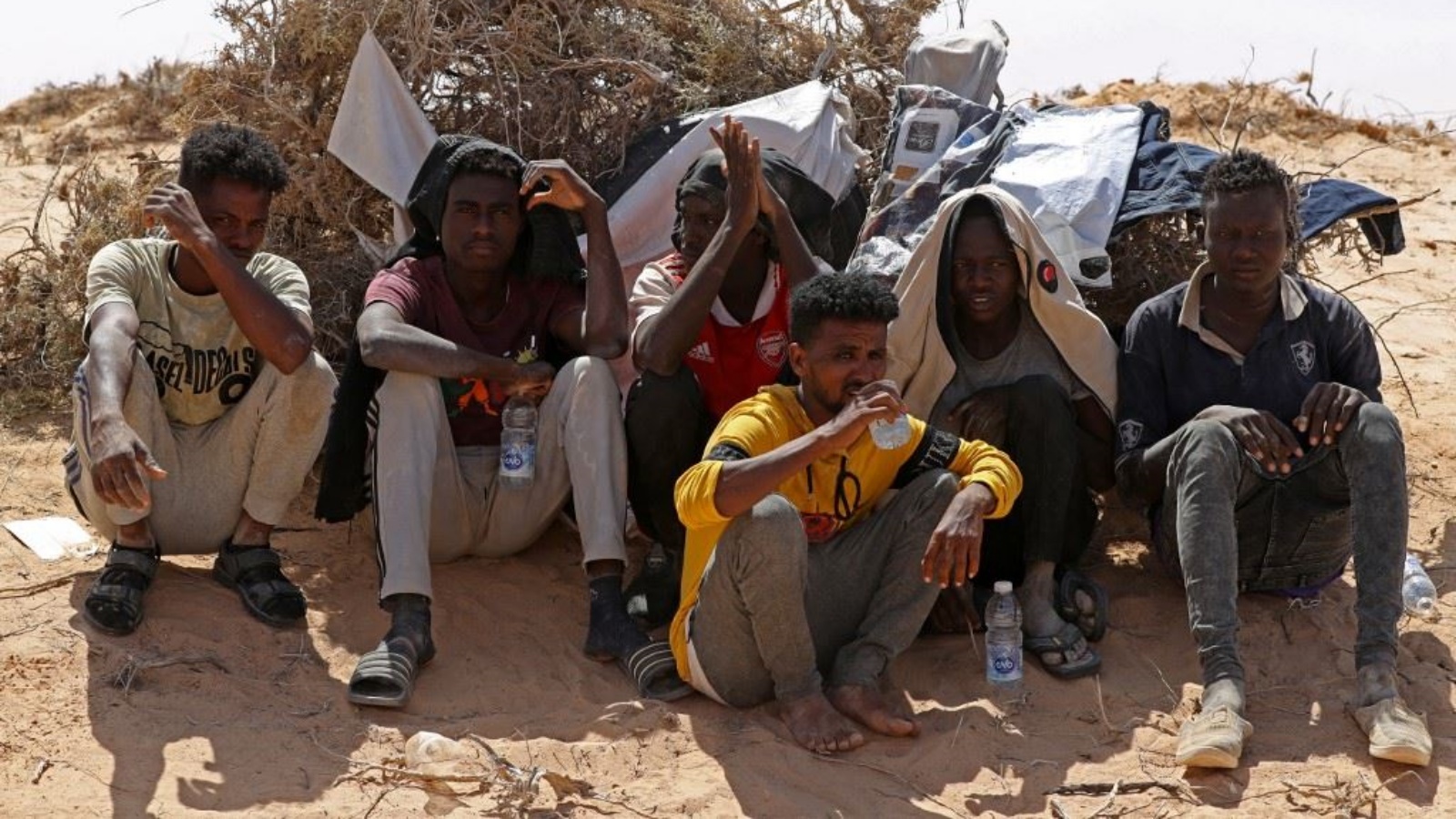 مهاجرون من أفريقيا جنوب الصحراء زعموا أن السلطات التونسية تركتهم في الصحراء دون ماء أو مأوى، جلسوا في منطقة غير مأهولة بالقرب من مدينة العسة الحدودية الليبية 16 يوليو 2023