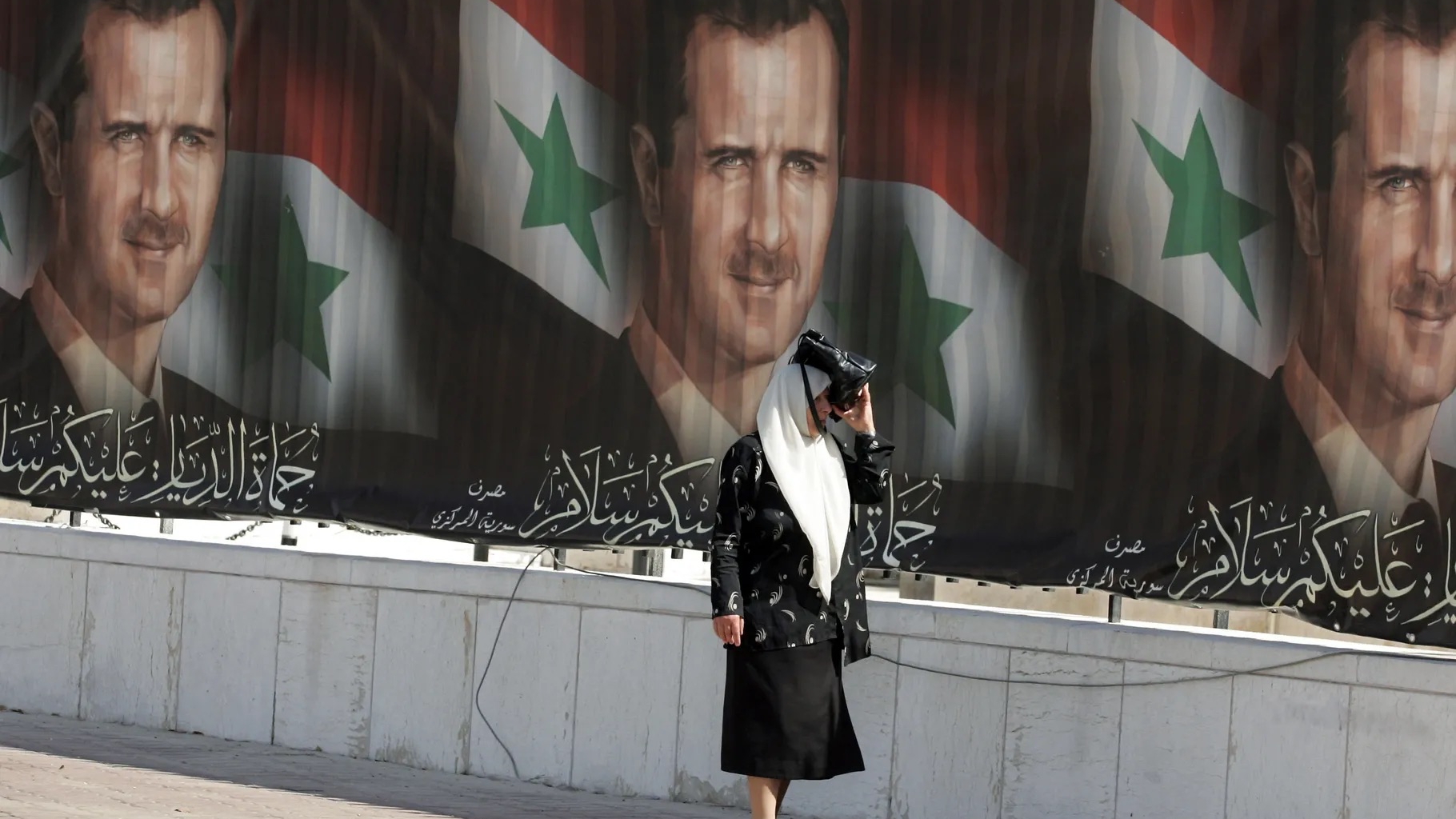 امرأة تمر بجوار رسم للرئيس السوري بشار الأسد