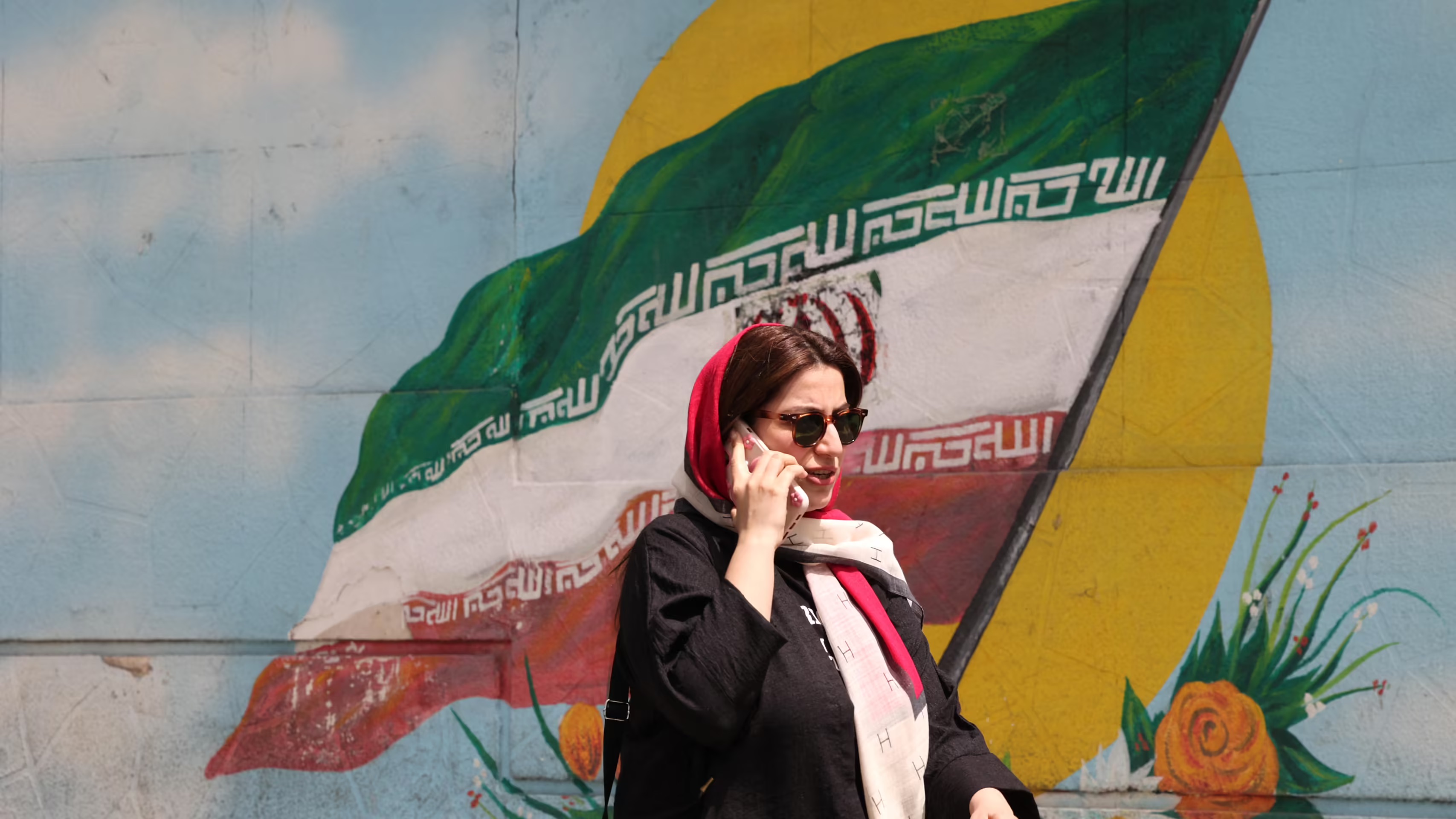 امرأة تسير في طهران في العاشر من نيسان (أبريل) ويبدو خلفها العلم الإيراني