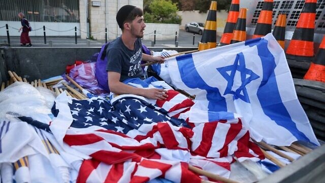 استعدادا لزيارة جو بايدن إلى اسرائيل، عامل يجهز الأعلام الإسرائيلية والأميركية في القدس يوم 12 تموز (يوليو) 2022