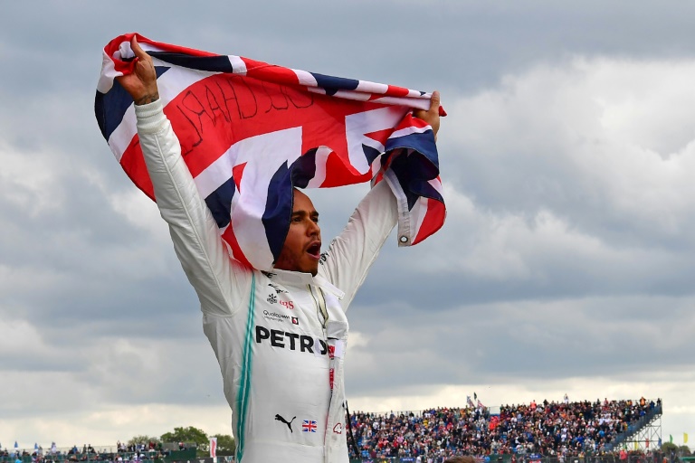 سائق مرسيدس البريطاني لويس هاميلتون يرفع علم المملكة المتحدة بعد فوزه على حلبة سيلفرستون في 14 تموز/يوليو 2019.