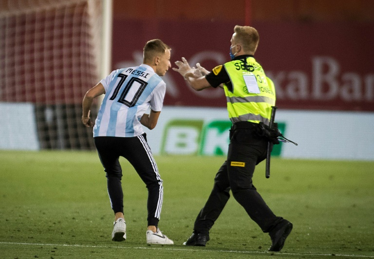 رجل أمن يسعى الى توقيف مشجع اقتحم أرض ملعب مباراة ريال مايوركا وضيفه برشلونة ضمن الدوري الإسباني لكرة القدم، في 13 حزيران/يونيو 2020.