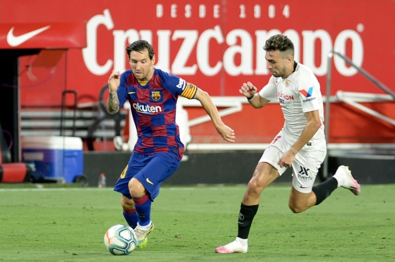 نجم برشلونة الدولي الارجنتيني ليونيل ميسي يحاول تخطي زميله السابق في النادي الكاتالوني مهاجم اشبيلية منير الحدادي في مباراة الفريقين في الدوري الاسباني في 19 حزيران/يونيو 2020.