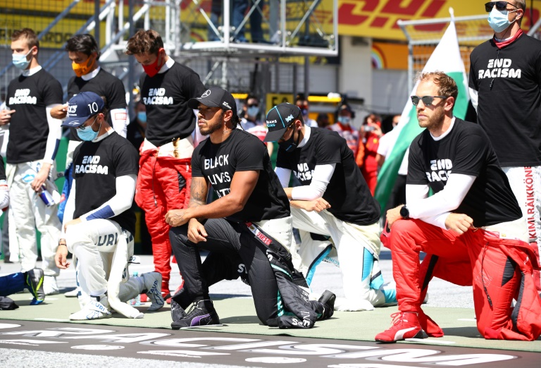 البريطاني لويس هاميلتون (وسط) والألماني سيباستيان فيتل (الى اليمين) يتقدمان السائقين على ركبة واحدة قبل جائزة النمسا الكبرى، في الخامس من تموز/يوليو 2020.