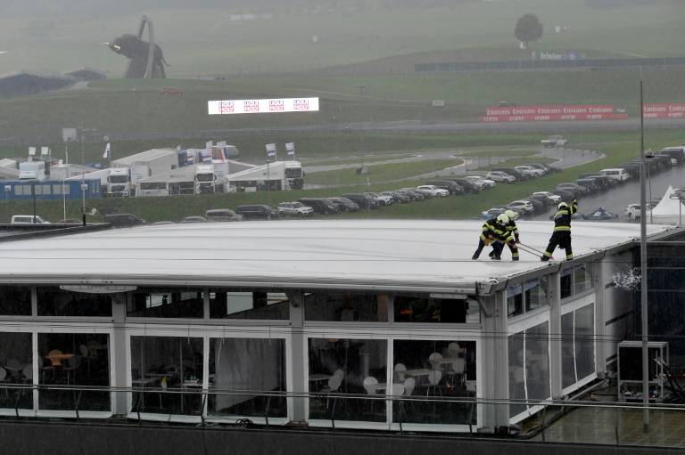 عناصر من فوج الاطفاء يزيلون المياه عن سطح أحد مباني حلبة ريد بول رينغ في النمسا، في 11 تموز/يوليو 2020.