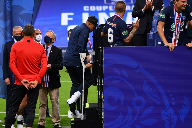مهاجم باريس سان جرمان كيليان مبابي يستخدم عكازين للصعود الى منصة تتويج فريقه بلقب كأس فرنسا لكرة القدم، في 24 تموز/يوليو 2020.
