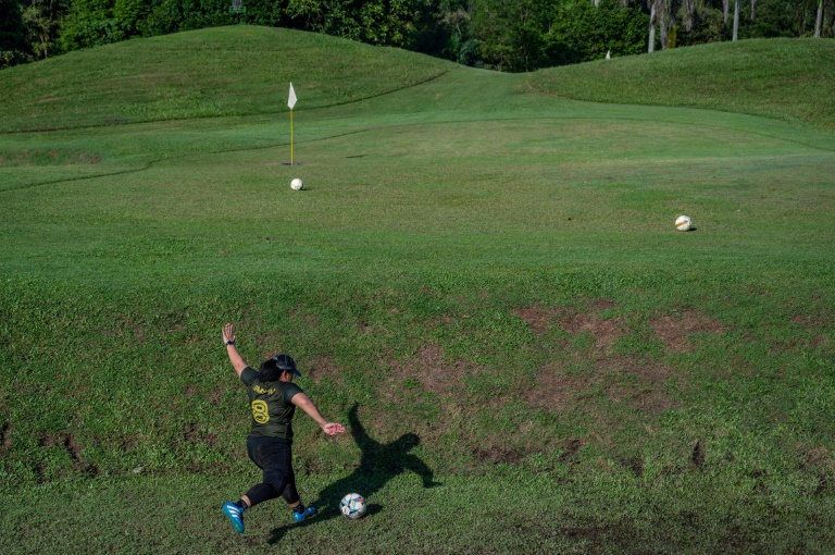 جمياتول أكمل عبد الجبار تركل كرة قدم في اتجاه حفرة غولف خلال مزاولتها رياضة 