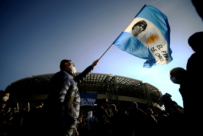 احد مشجعي نادي نابولي الإيطالي يرفع العلم الارجنتيني وفي وسطه صورة الاسطورة دييغو مارادونا أمام ملعب الفريق الجنوبي، في 26 تشرين الثاني/نوفمبر 2020