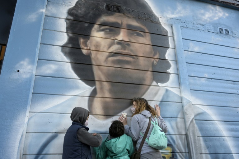 عشاق النجم الارجنتيني الراحل دييغو أرماندو مارادونا أمام لوحة جدارية له في بوينس أيرس في 22 حزيران/يونيو 2021.