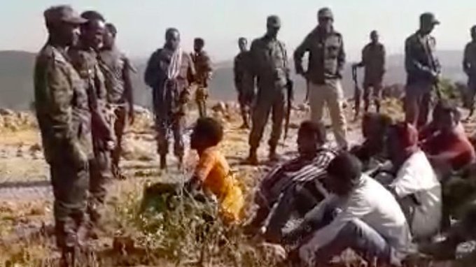 الفيديو يُظهر مجموعة من الرجال في زي مدني يجلسون على الأرض قبل المجزرة