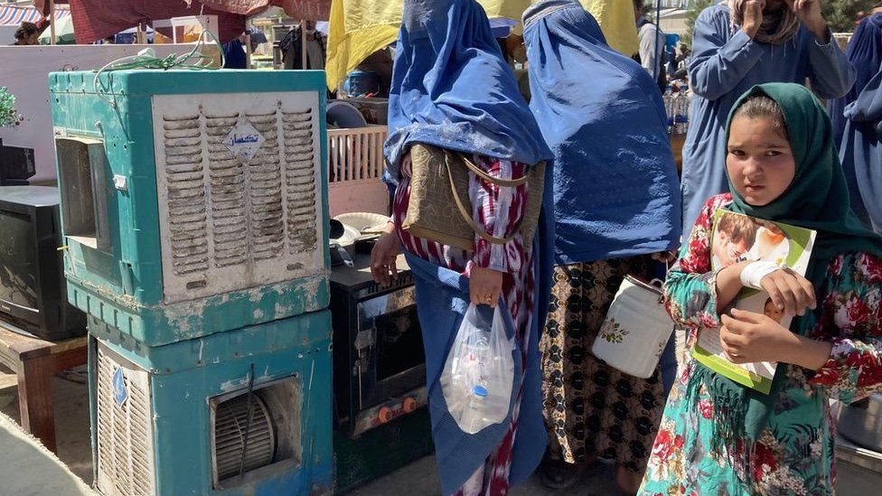 فتاة في سوق للأغراض المستعملة في مزار الشريف في أفغانستان حيث اضطر بعض الأفغان لبيع ممتلكاتهم لتغطية نفقاتهم