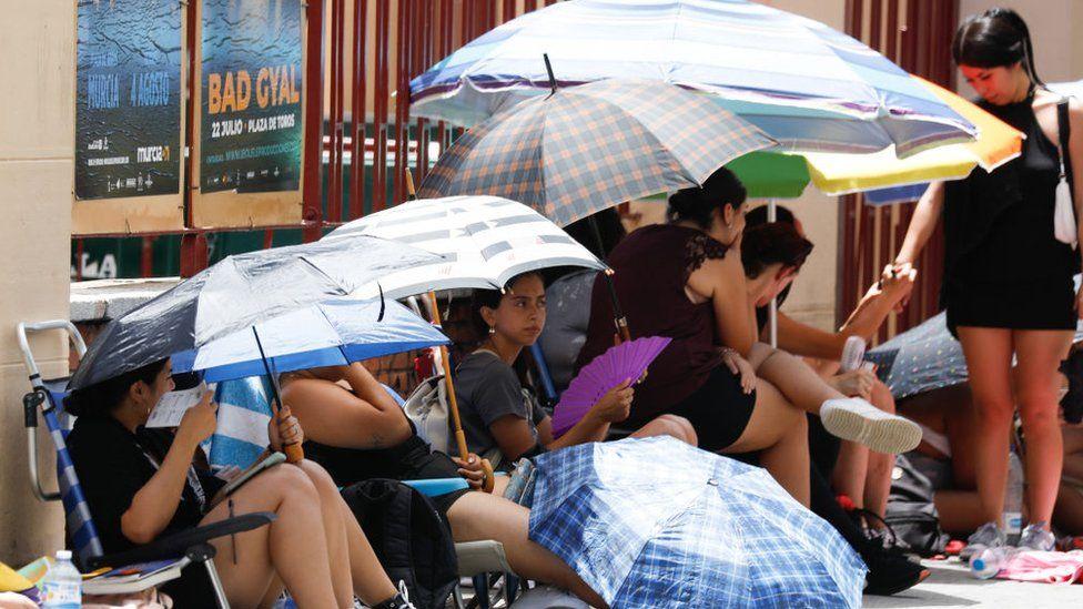 عدد من الأشخاص يحتمون من أشعة الشمس مستعينين بالمظلات في مدينة مُرسية جنوب شرقي إسبانيا