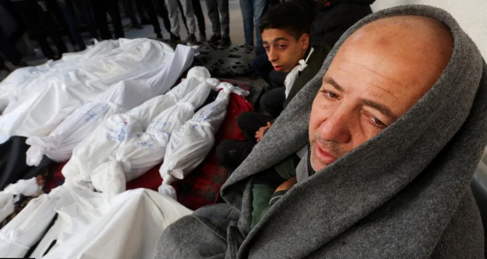 Reuters | شبان يجلسون بجوار جثث عند معبر رفح يوم الثلاثاء الماضي
