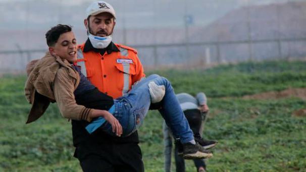 Getty Images | المسعف أحمد أبو فول يحمل فتى مصاباً