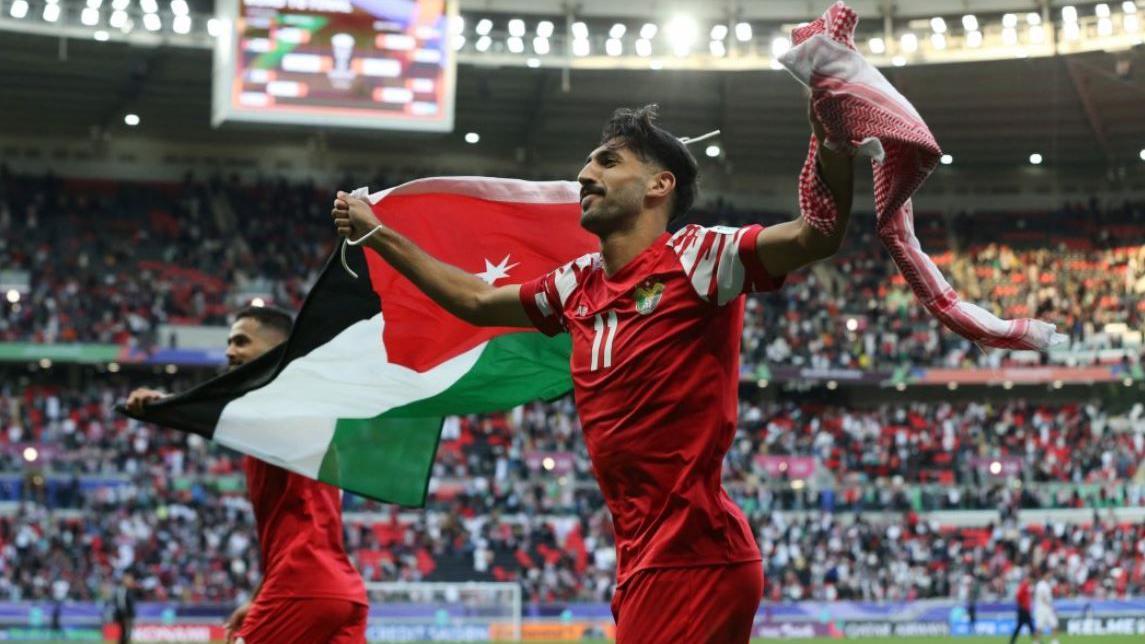 Reuters | اللاعب الأردني يزن النعيمات يحمل العلم الأردني ويحتفل بفوز منتخب بلاده على منتخب طاجيكستان