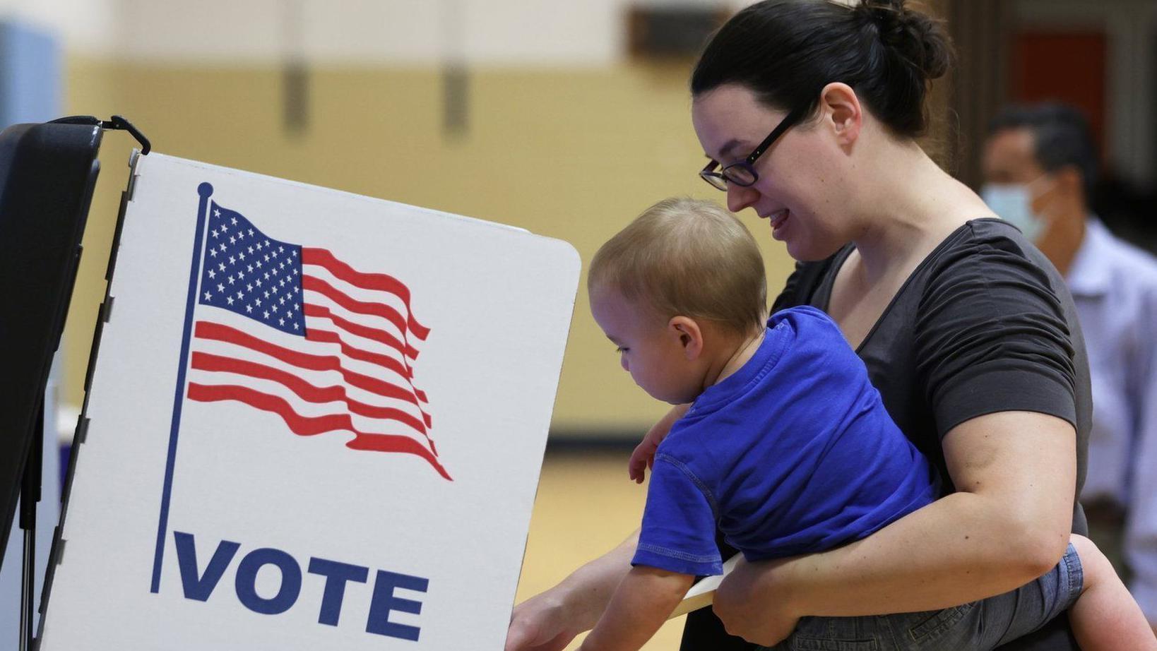 امرأة تحمل طفلاً تدلي بصوتها في الانتخابات التمهيدية الأميركية في ولاية فرجينيا