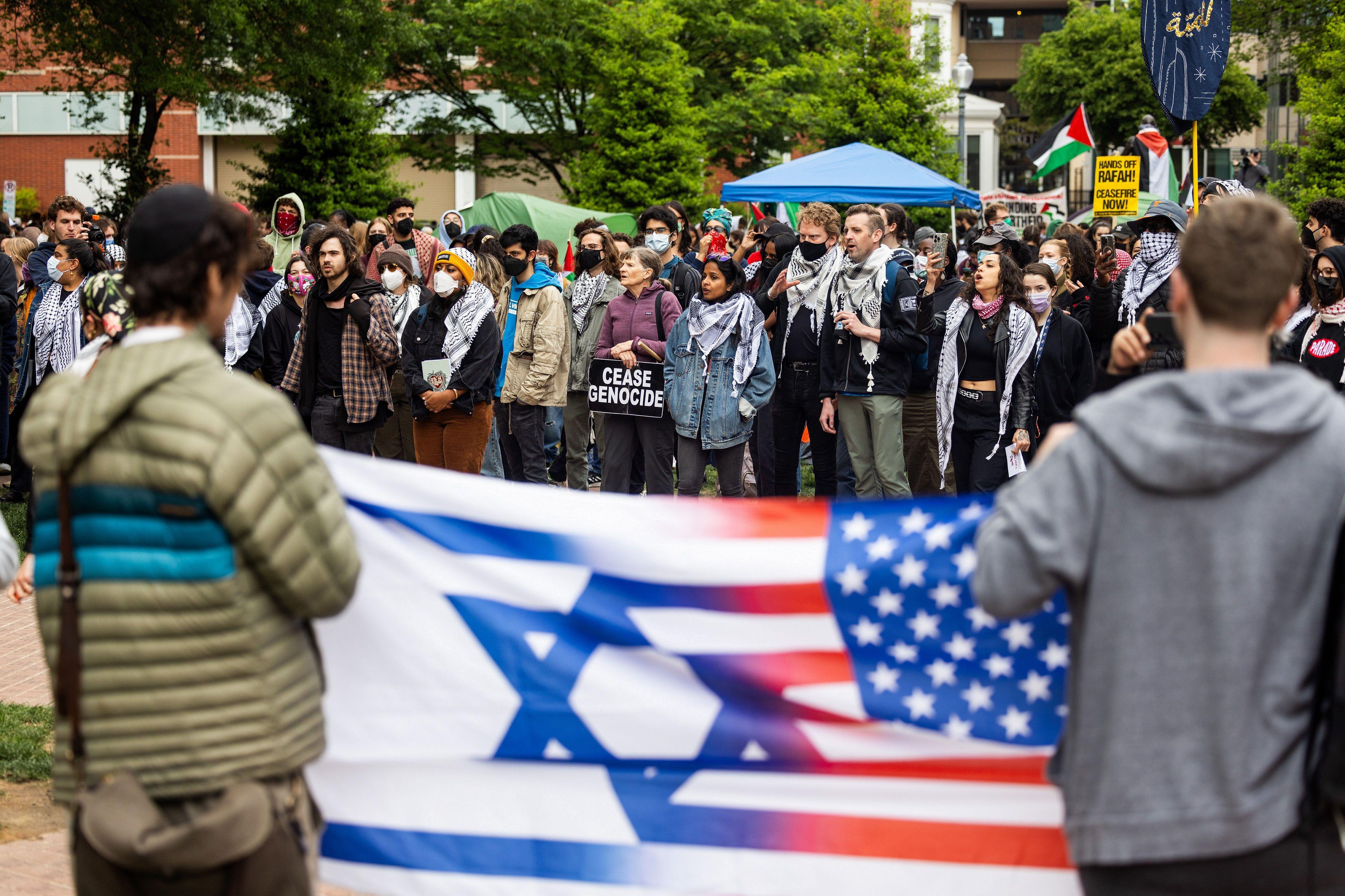 اثنان من أنصار إسرائيل يحملان العلم الأميركي والإسرائيلي أمام المتظاهرين المؤيدين للفلسطينيين في جامعة جورج واشنطن