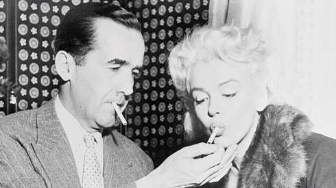 المذيع إدوارد ر مورو يشعل سيجارة النجمة مارلين مونرو أثناء المناقشات في فندق أمباسادور في نيويورك بشأن ظهورها في برنامج مورو التلفزيوني