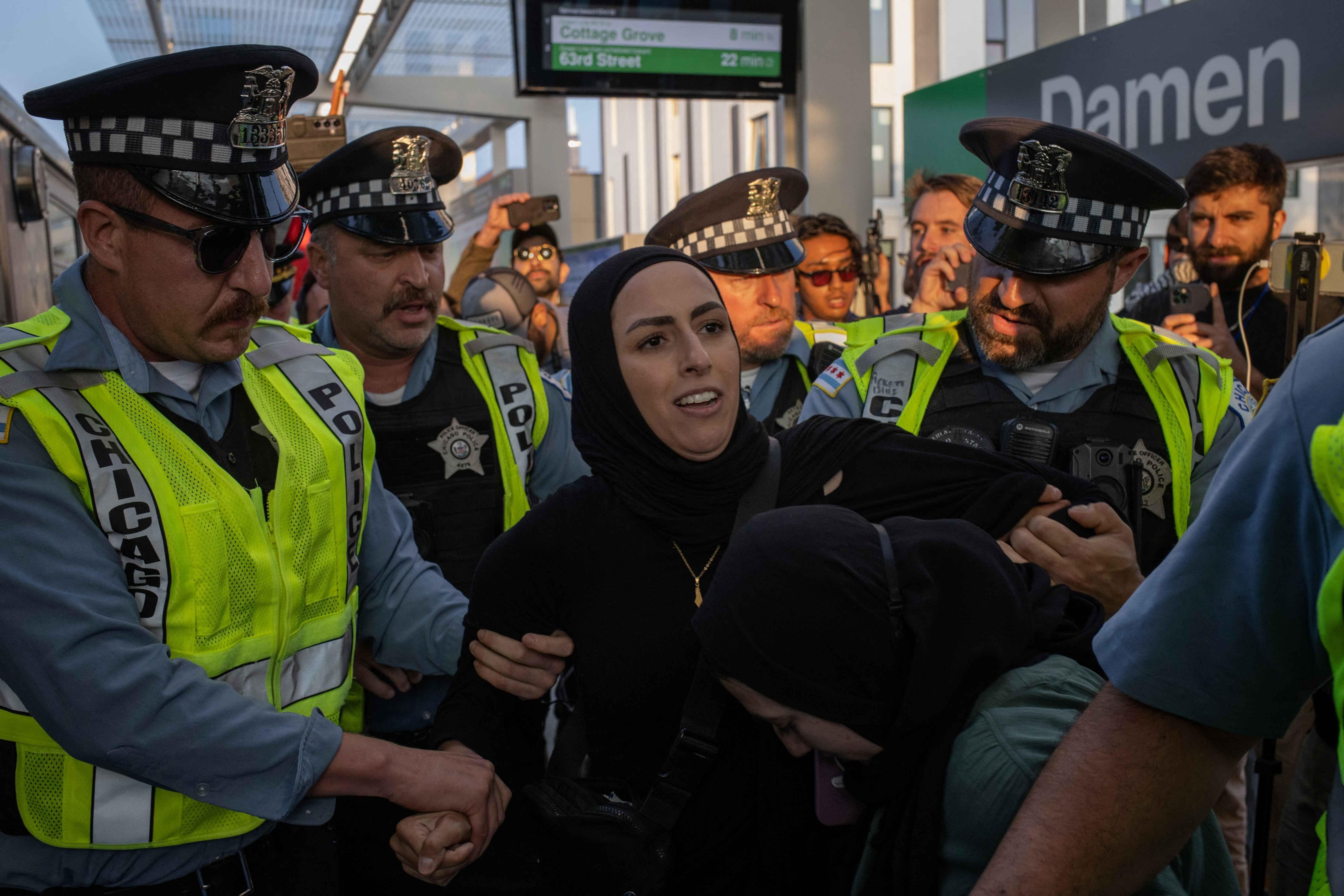 احتجزت الشرطة الأمريكية نساء يرتدين الحجاب، كن يصورن مسيرة احتجاجية مؤيدة للفلسطينيين، على طول رصيف محطة قطار دامين، في شيكاغو يوم 21 أغسطس 2024