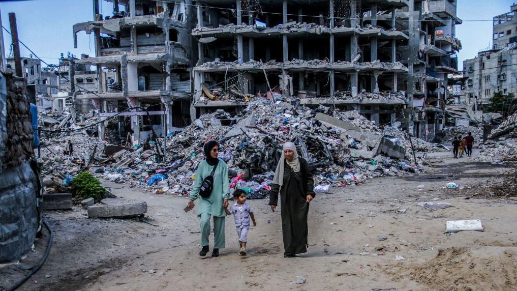 فلسطينيون يسيرون بجوار مبانٍ مدمرة جراء القصف الإسرائيلي في مخيم جباليا شمال غزة