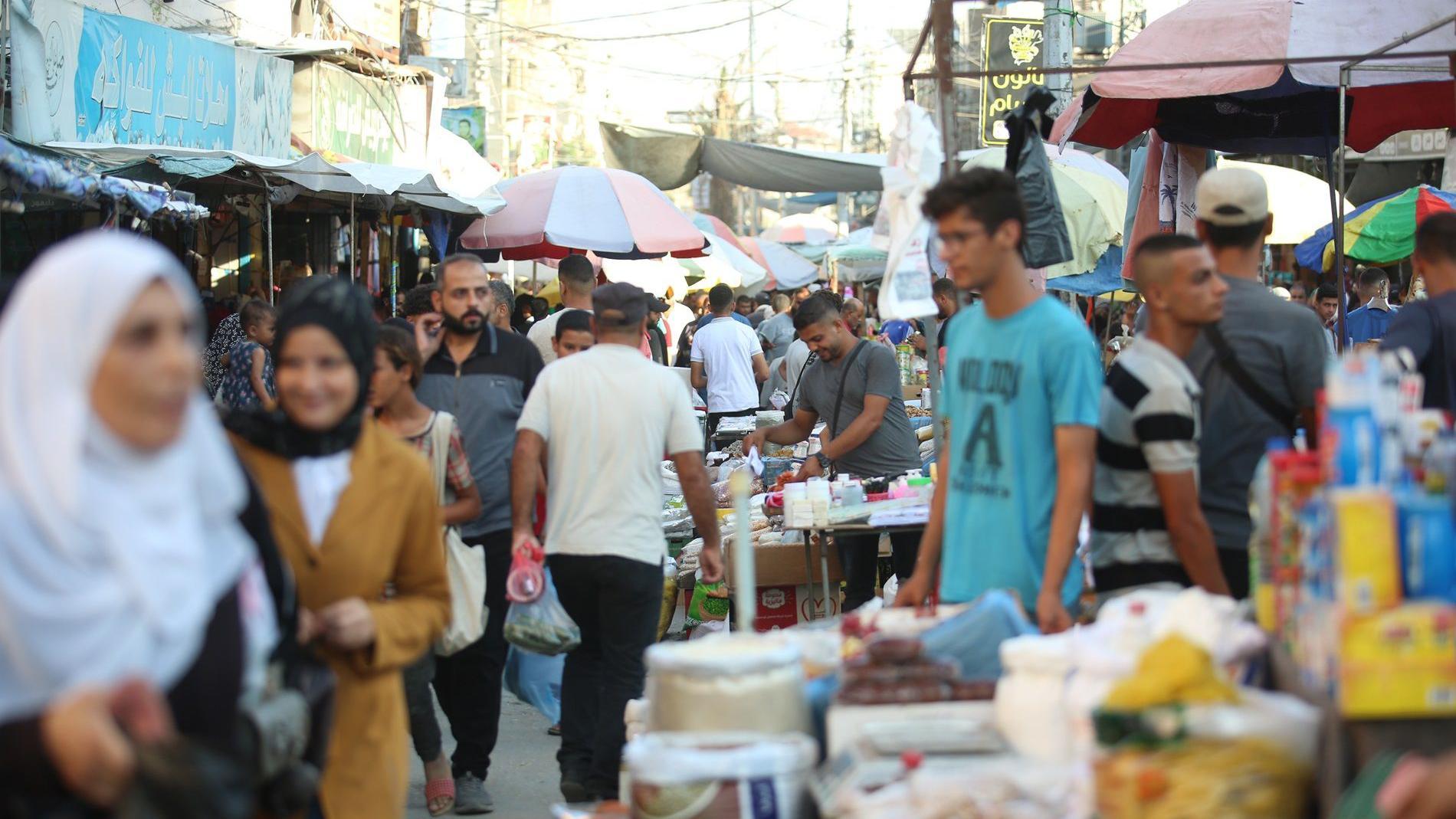 يتسوق فلسطينيون في سوق شعبي أقيم بين المباني المدمرة نتيجة للهجمات الإسرائيلية، بينما تستمر الحياة اليومية في مخيم النصيرات للاجئين في مدينة غزة