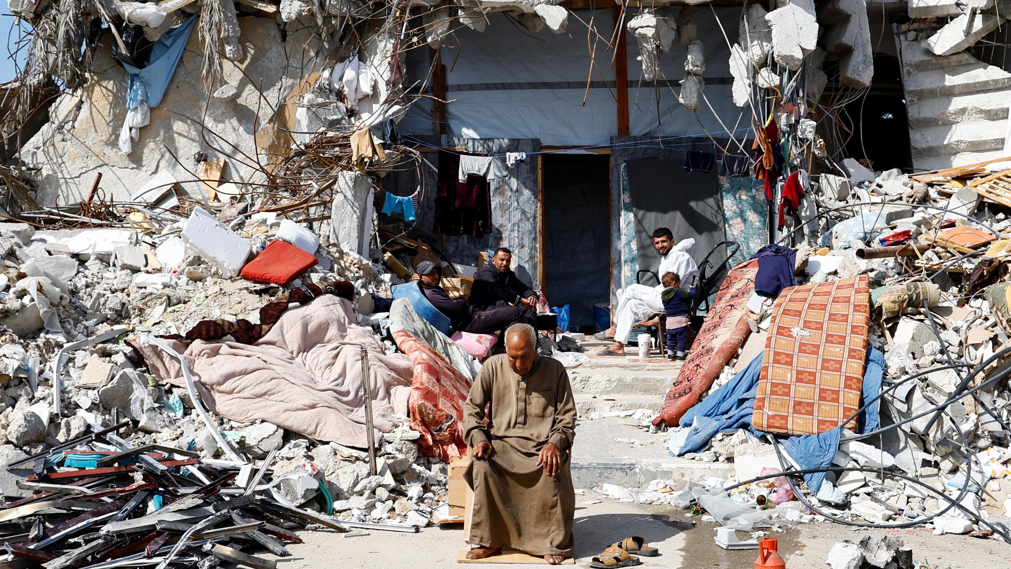 فلسطينيون يجلسون وسط أنقاض المباني المدمرة في غزة - Reuters