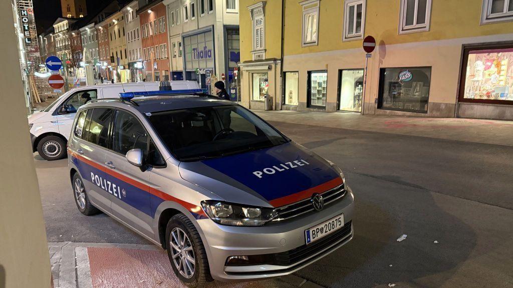 سيارة شرطة في أحد شوارع فيلاخ، لونها رمادي ومدهونة بشكل جزئي من الأمام والجانب بلون كحلي وخط رفيع أحمر. تصطف في شارع قرب بنايات بطابع أوروبي. الصورة التقطت ليلاً. - Getty Images