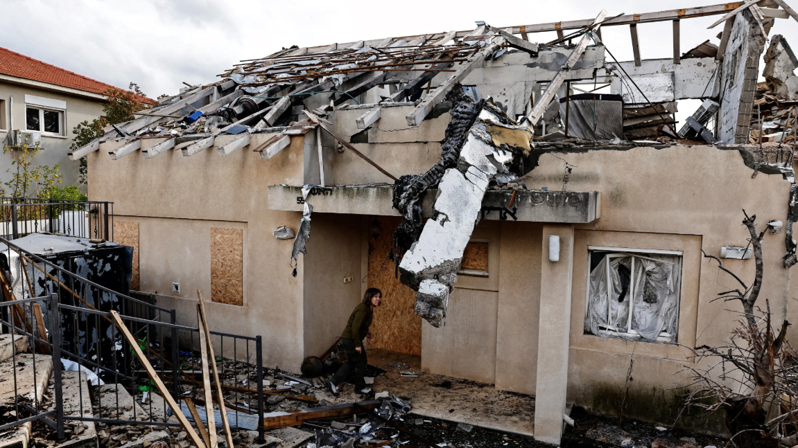 امرأة تحتمي بمدخل بيت تعرّض للقصف - Reuters