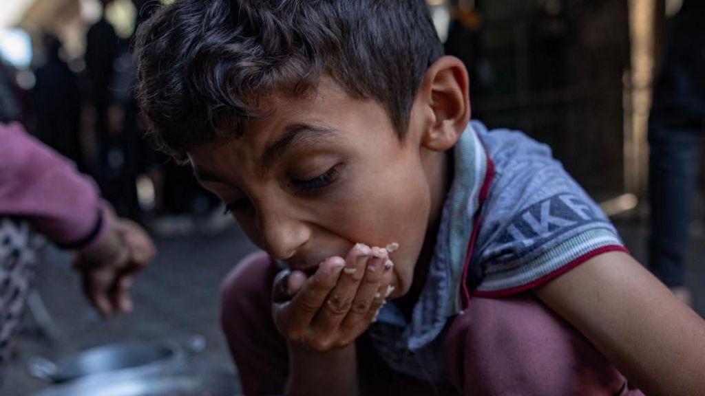 طفل فلسطيني جائع يتناول الطعام في قطاع غزة - EPA