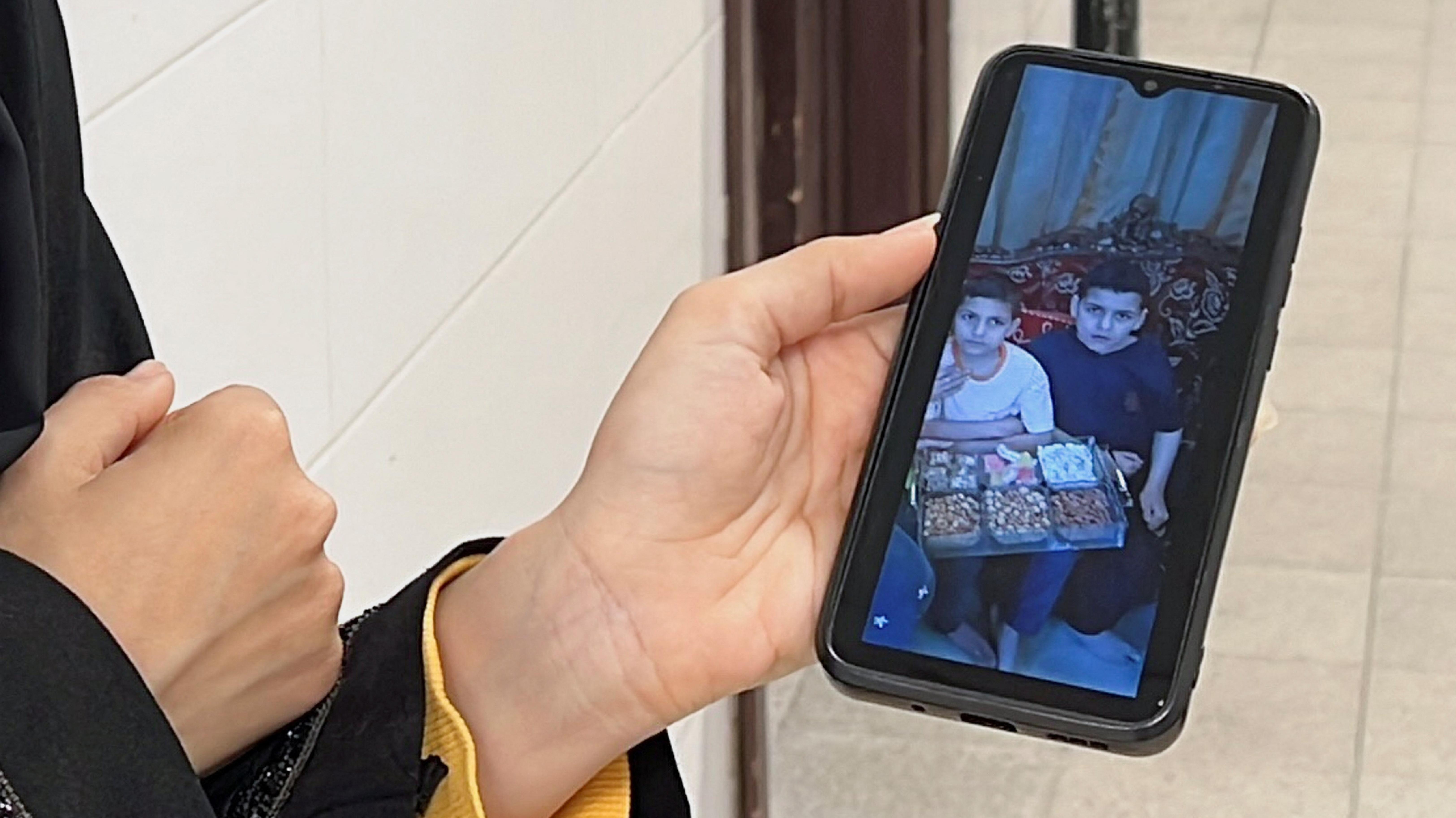 امرأة فلسطينية تعرض على هاتفها المحمول أطفال عائلة النجار الذين قتلوا في غارة جوية إسرائيلية في خان يونس جنوب قطاع غزة - Reuters