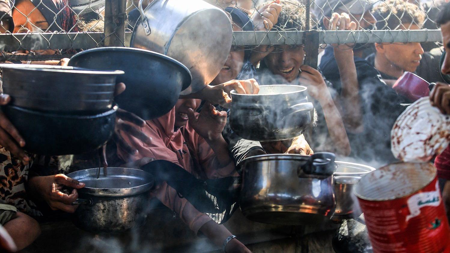خان يونس، غزة - 30 مايو/أيار: نازحون فلسطينيون، بينهم نساء وأطفال، يعيشون في خيام، يتلقون مساعدات غذائية وزعتها منظمات الإغاثة في منطقة المواصي بخان يونس، غزة. يُبرز هذا الوضع تنامي اليأس والحاجة المُلِحّة للمساعدات الإنسانية في القطاع المُحاصر. - Getty Images