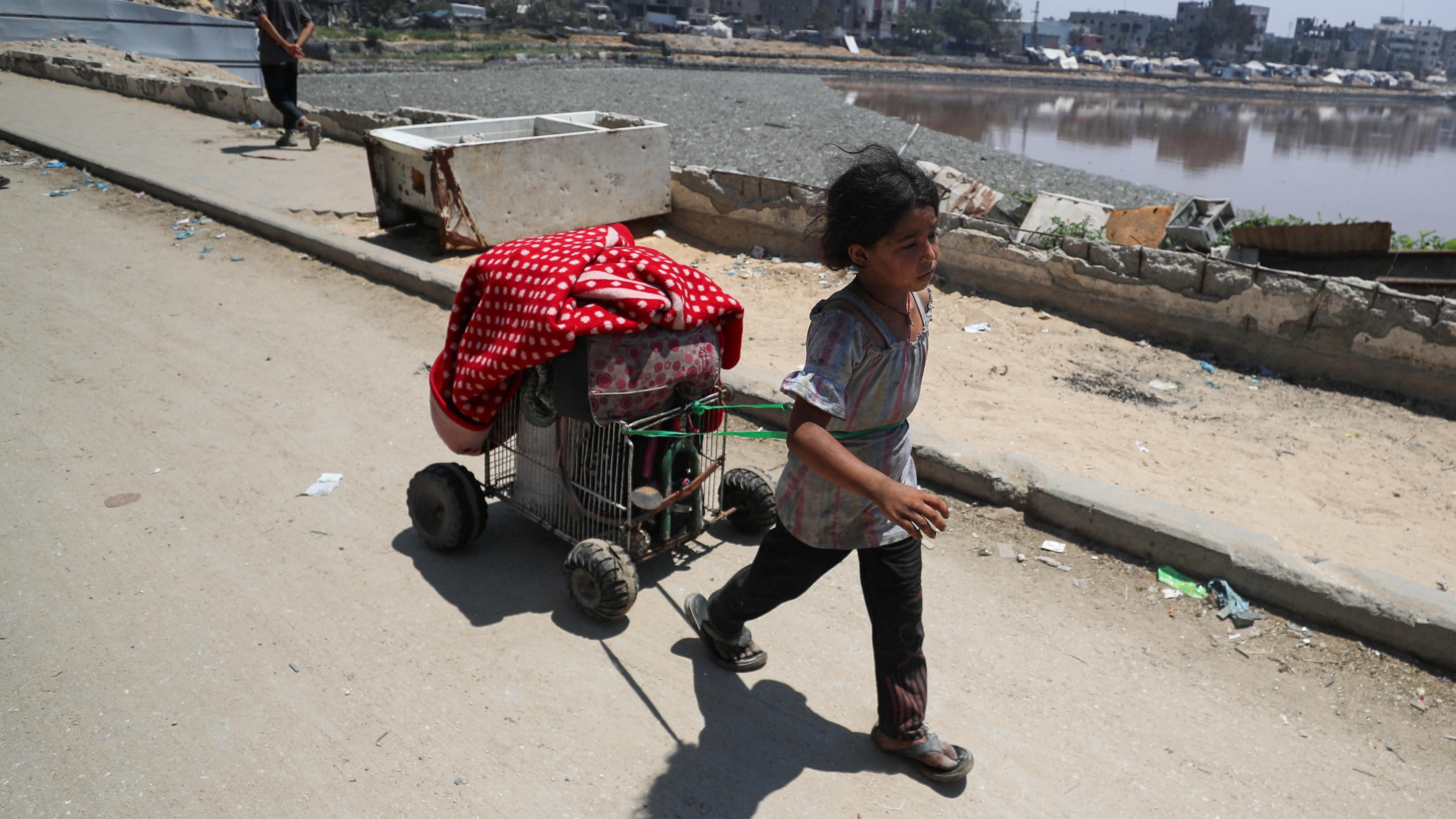 صورة تظهر طفلة فلسطينية تجرّ عربة صغيرة خلال نزوحها عن منزلها في مدينة غزة نهاية يونيو/حزيران. - Reuters