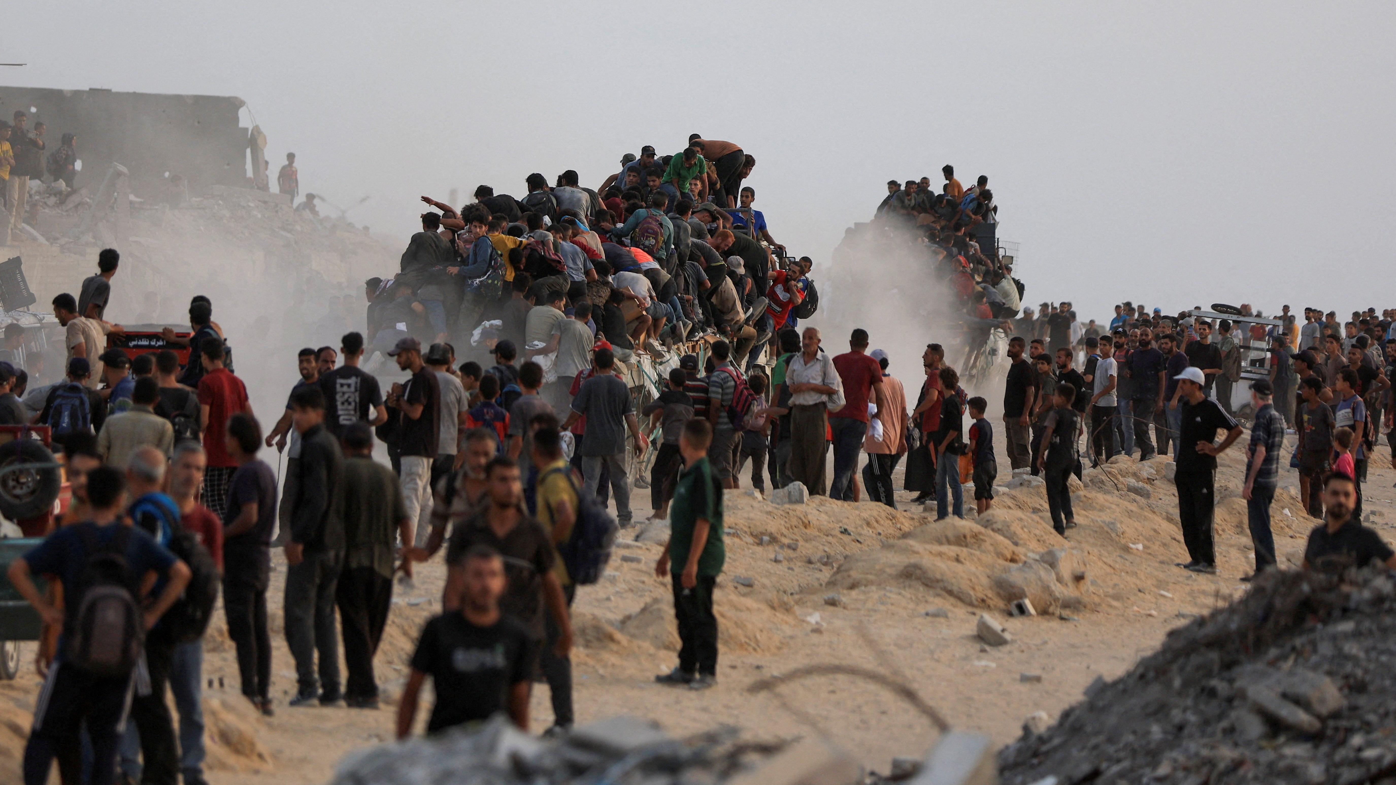 فلسطينيون يصعدون إلى شاحنات محملة بمساعدات دخلت غزة في 29 يوليو/تموز 2025 - Reuters