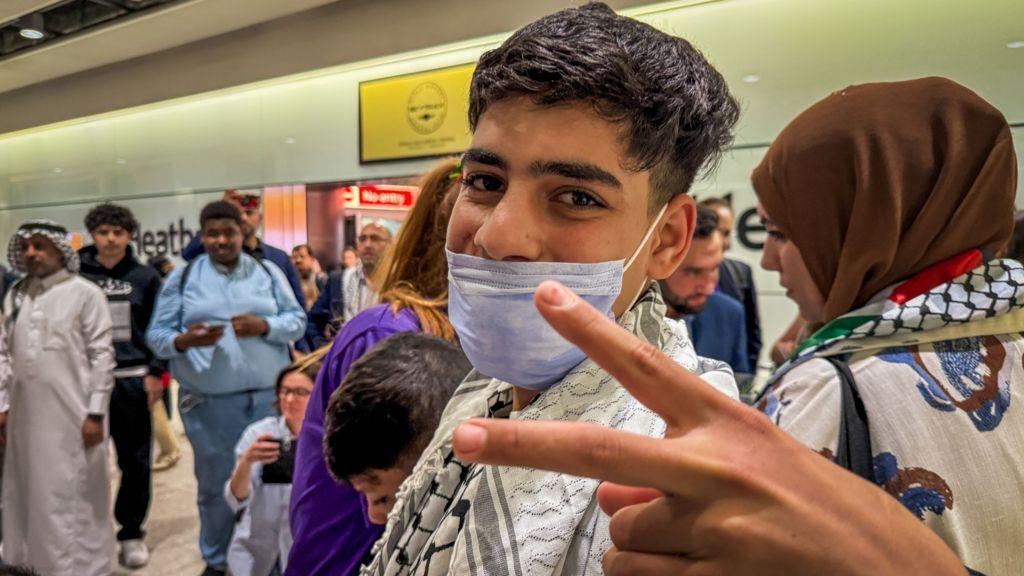 ماجد شغنوبي يصل إلى مطار هيثرو في لندن وهو يرتدي الكوفية الفلسطينية ويشير بعلامة النصر - BBC