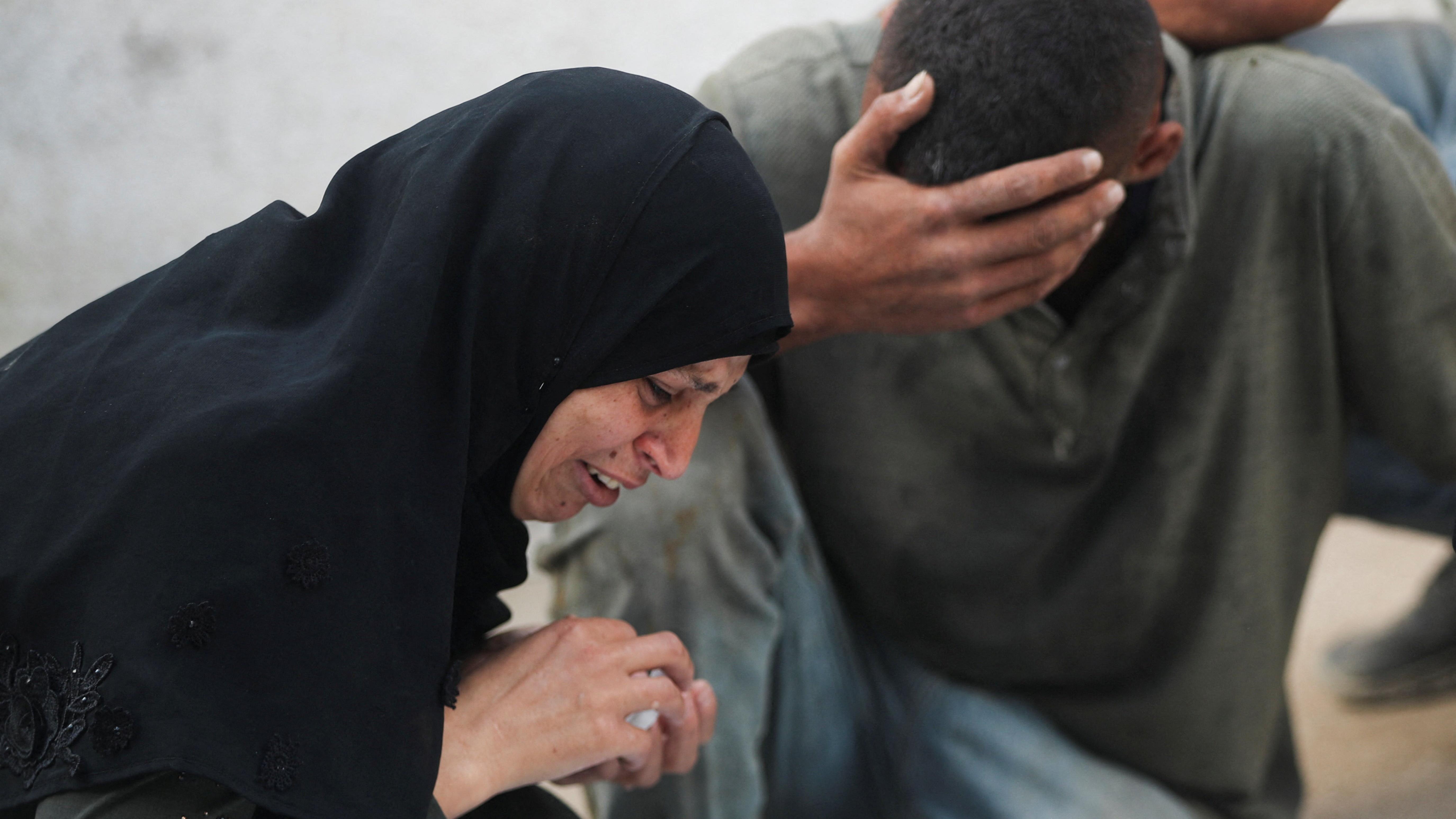 رجل وامرأة فلسطينيان يبكيان على أحد أفراد أسرتهما الذي قتل في استهداف إسرائيلي لتجمعات مواطنين حاولوا الحصول على مساعدات إنسانية - Reuters
