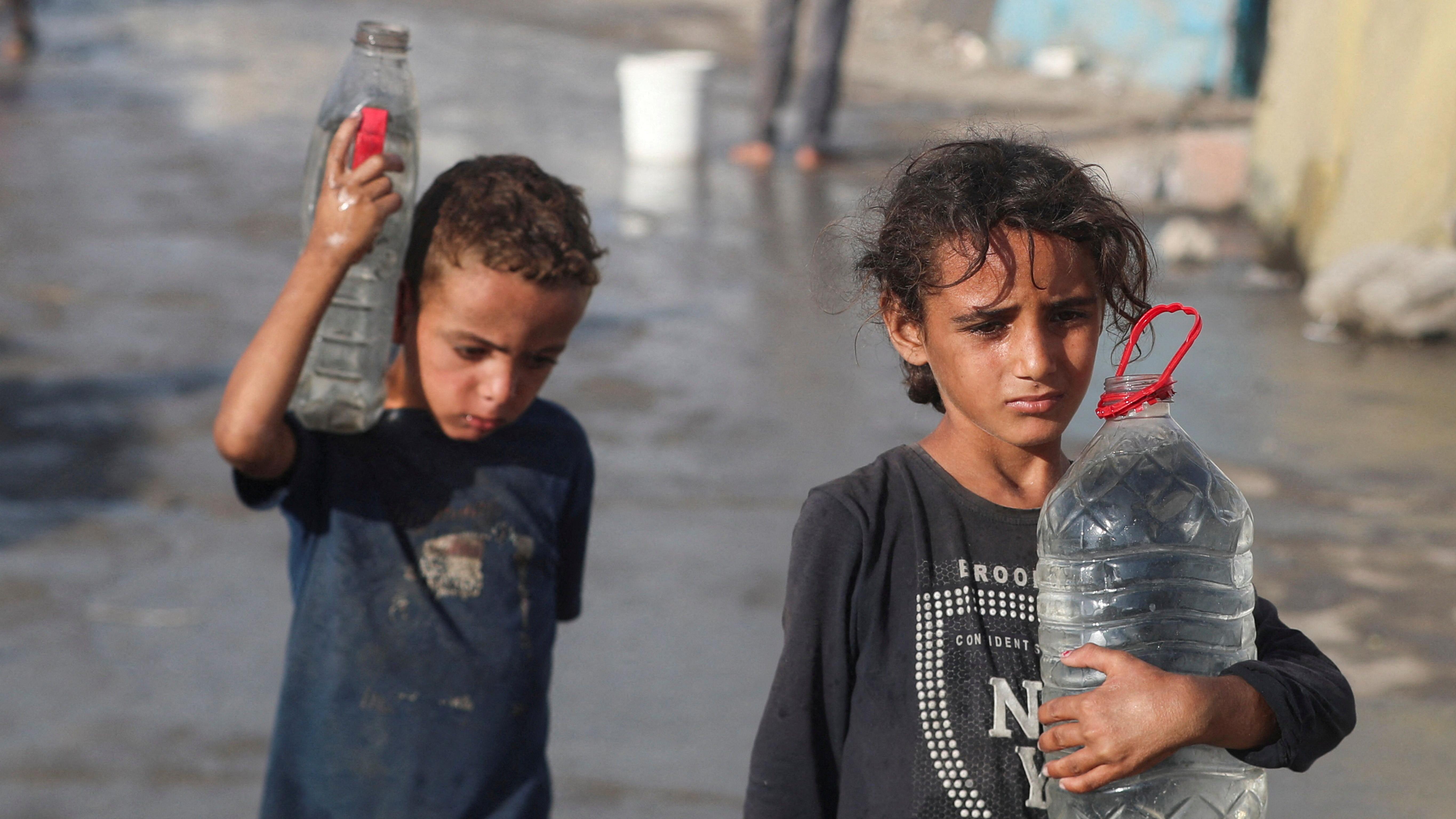 طفلان في غزة يحملان أوعية فيها ماء - Reuters