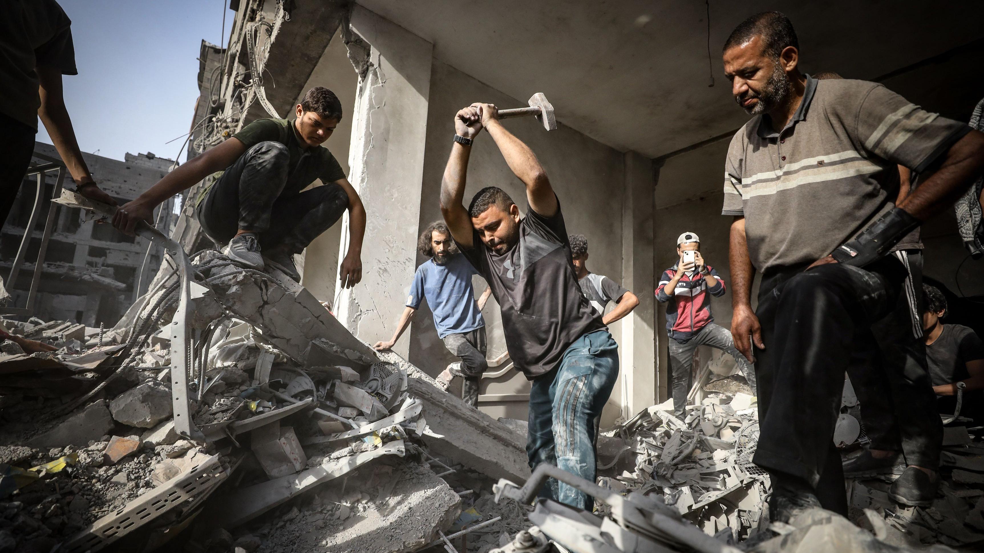 فلسطينيون يحاولون سحب جثة طفل تحت الأنقاض بعد هجمات إسرائيلية على مخيم الشاطئ غرب مدينة غزة - Anadolu via Getty Images