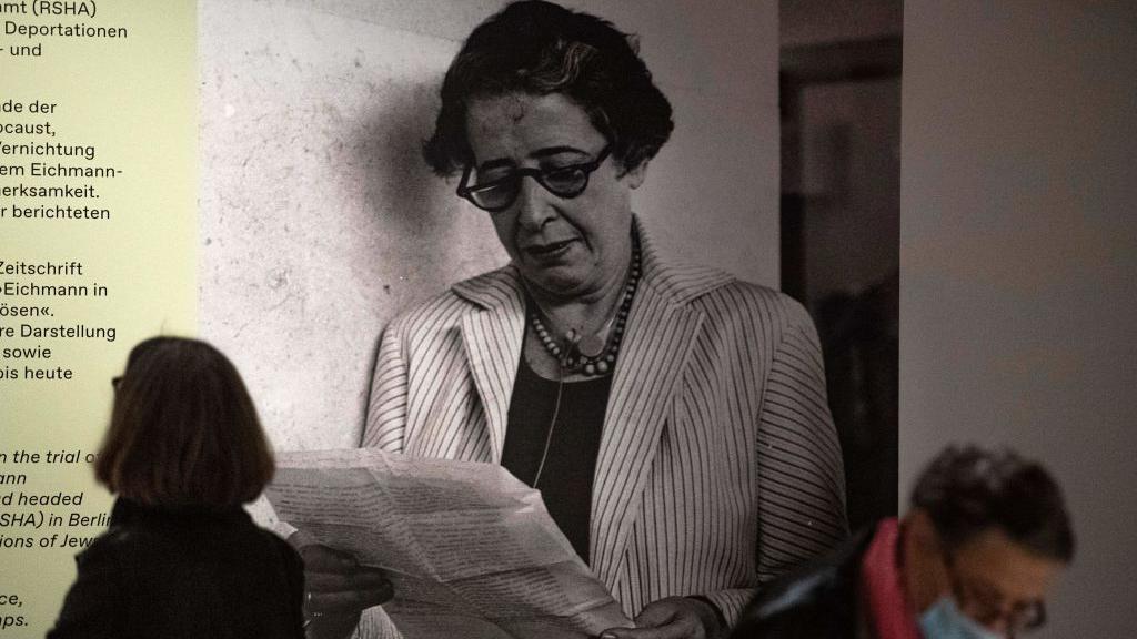 أحد الزوّار إلى جانب صورة للفيلسوفة والمنظّرة السياسية الألمانية-الأمريكية حنّة آرنت خلال العرض التمهيدي للصحافة لمعرض 
