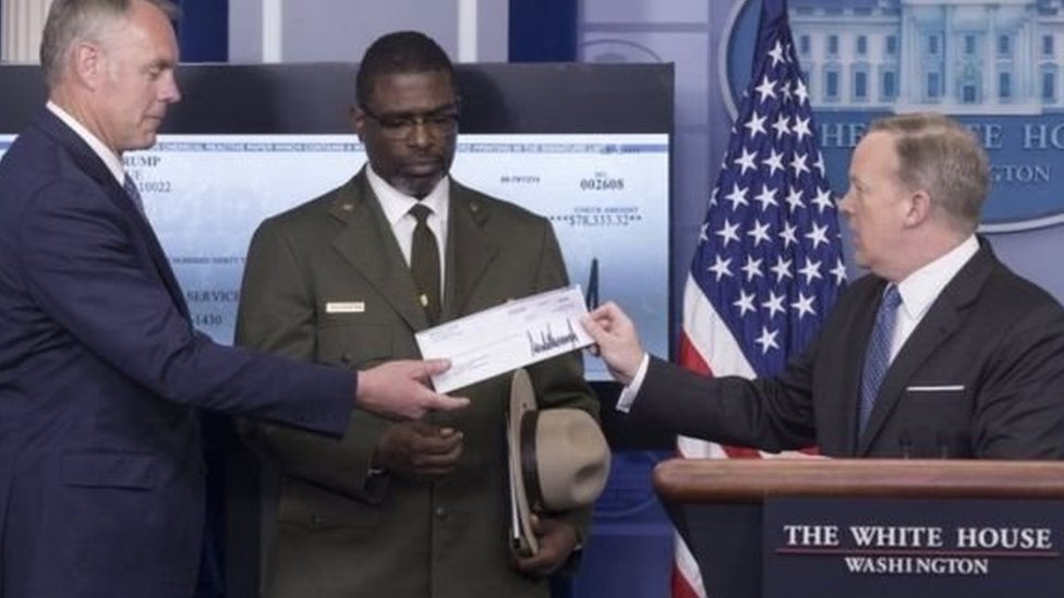 شون سبايسر المتحدث باسم البيت الأبيض يسلم وزير الداخلية شيكا بمبلغ التبرع.