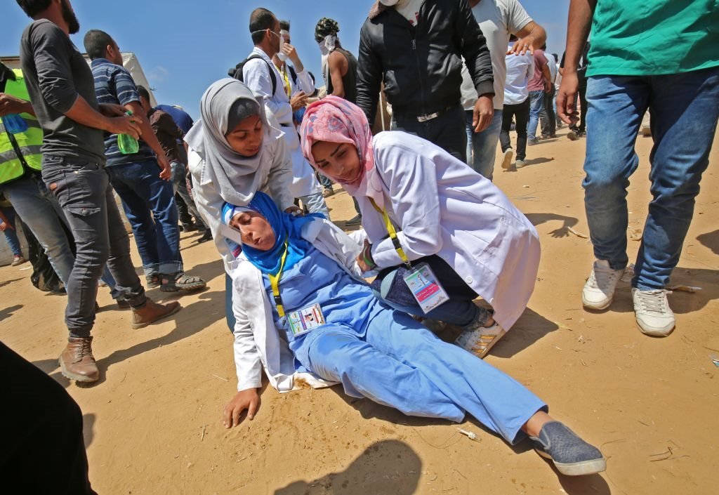 الممرضات الفلسطينيات يسارعن إلى مساعدة إحدى زميلاتهن خلال المصادمات مع الجيش الاسرائيلي في خان يونس جنوب قطاع غزة تنديدا بنقل واشنطن لسفارتها إلى القدس الذي تزامن مع ذكرى 