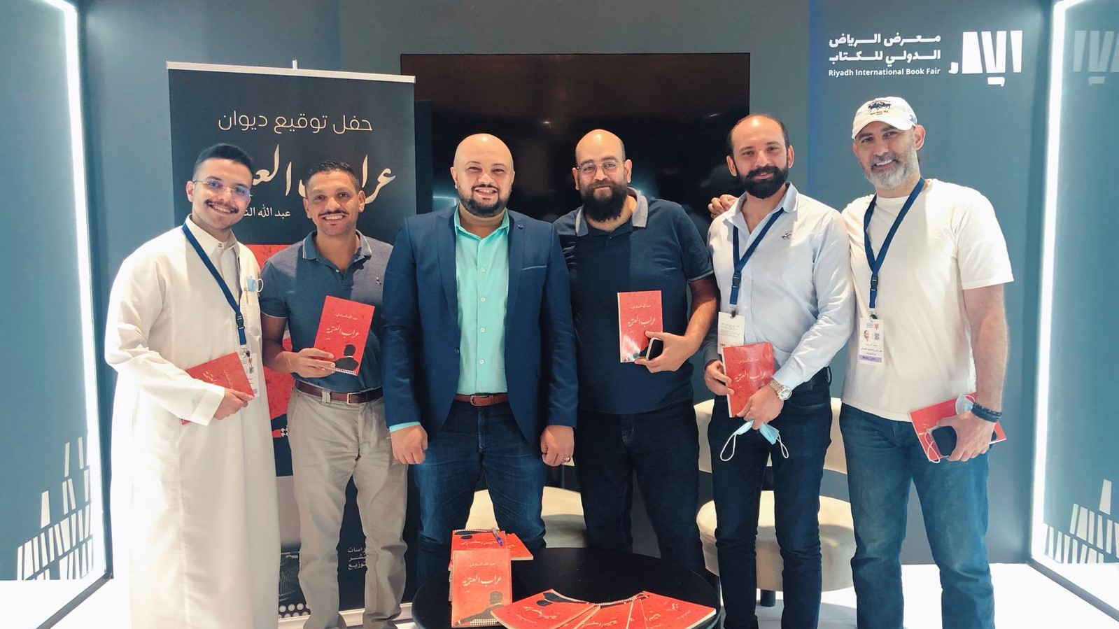 الشاعر والكاتب الصحافي عبدالله النادي محاطًا بالأصدقاء أثناء توقيعه مجموعته الشعرية "عراب العتمة" في معرض الرياض الولي للكتاب