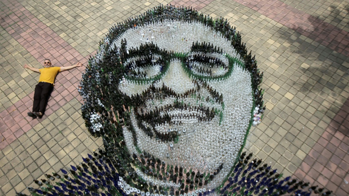 إدواردو بوترون إلى جانب مجسمه الذي اعاد فيه تكوين وجه الكاتب الكولومبي غابرييل غارسيا ماركيز في توباركو الكولومبية في الثاني من سبتمبر 2022 (ا ف ب)